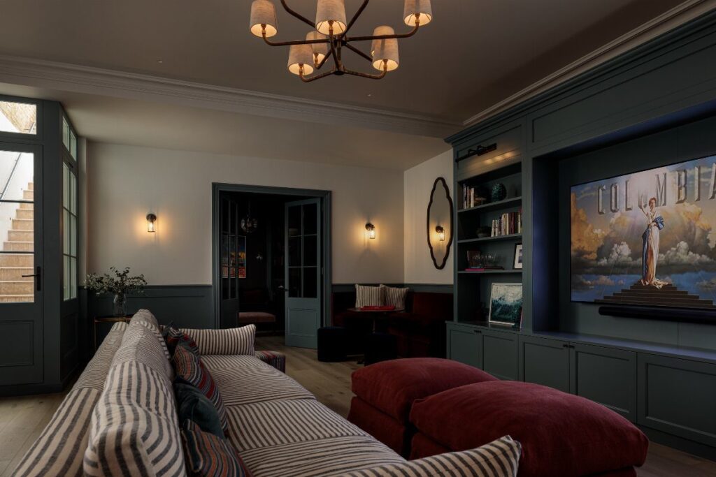 Modern basement living room with white walls and dark grey wainscoting and cabinetry.