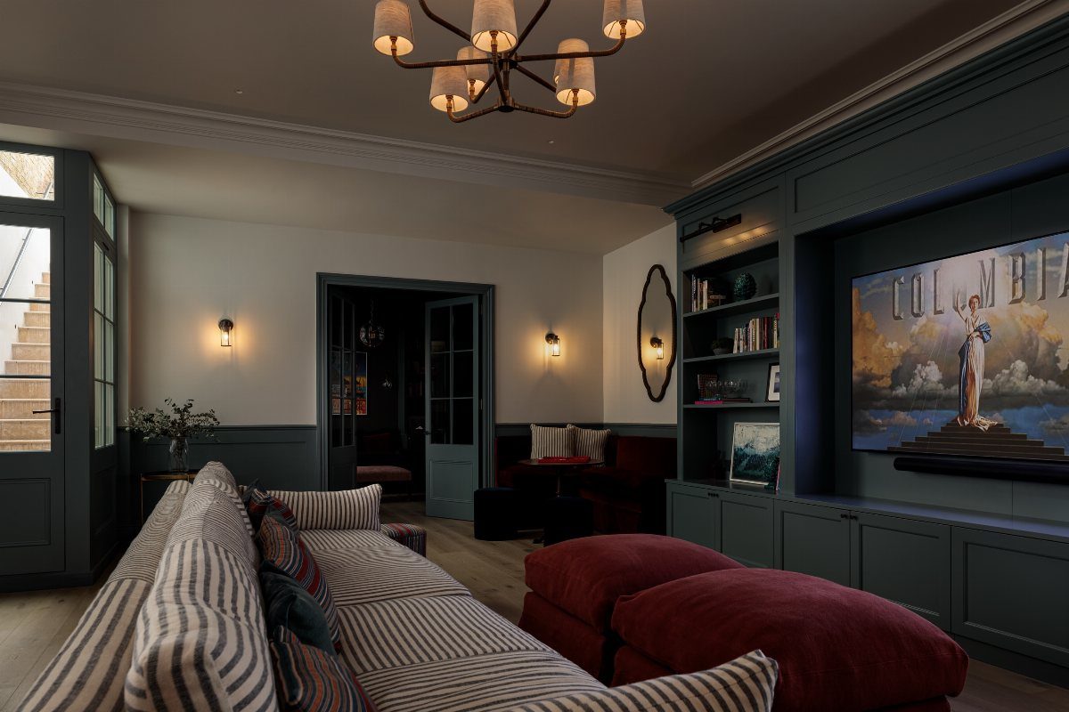 Modern basement living room with white walls and dark grey wainscoting and cabinetry.