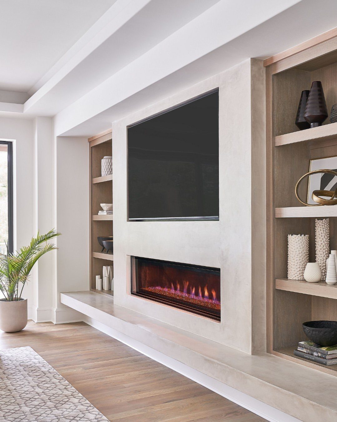Modern concrete fireplace wall with a mounted TV and built-in wooden shelving.