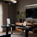 Modern home office with black L-shaped desk, leather chair, and abstract wall art.