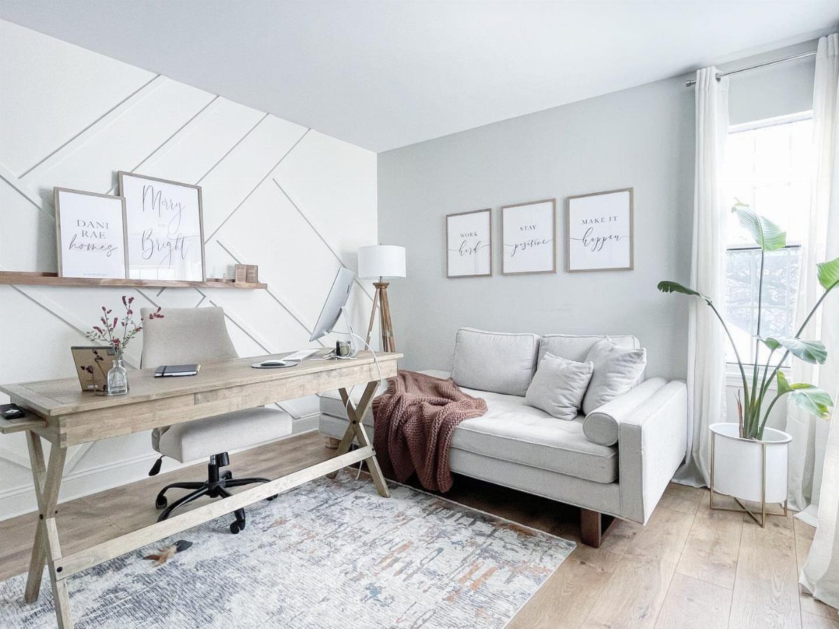 Home office with light gray walls, white geometric accent wall, and wooden desk.