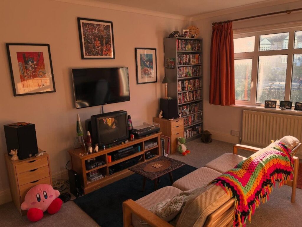 Retro video game room with CRT and flat-screen TVs, game shelves, and Kirby plush.